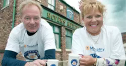 a picture of Bruce Jones and Cilla Brown standing outside the rovers return launching Motabilities tea party week.